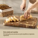 Une planche à découper Namture en bois XL avec un pain en cours de découpe. Un panier à pain est à l'arrière-plan.