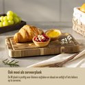Une planche à découper Namture avec un croissant, des tartelettes et des raisins, utilisée comme plateau de service.
