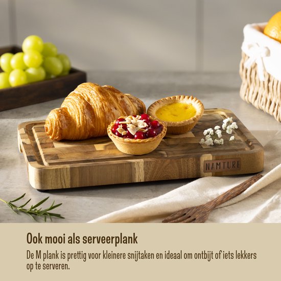 Une planche à découper Namture avec un croissant, des tartelettes et des raisins, utilisée comme plateau de service.