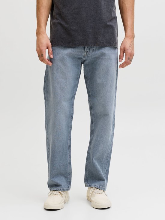 Voorste deel van een man in een donkergrijs t-shirt en een blauwe jeans met wijde pijpen.