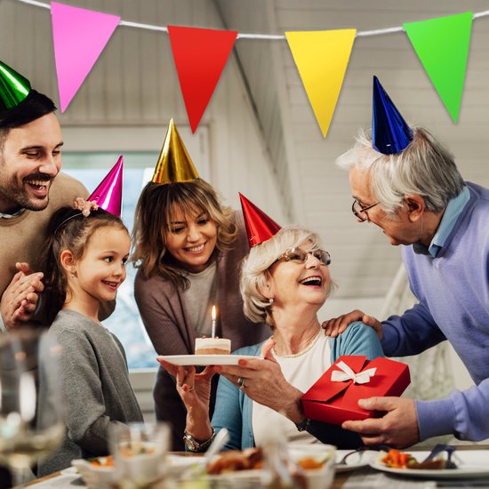 Une famille célèbre un anniversaire avec un gâteau, des cadeaux et des fanions multicolores.
