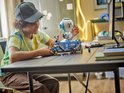 Un garçon construit le LEGO Fortnite Battle Bus avec ballon, avec des figurines sur le toit.