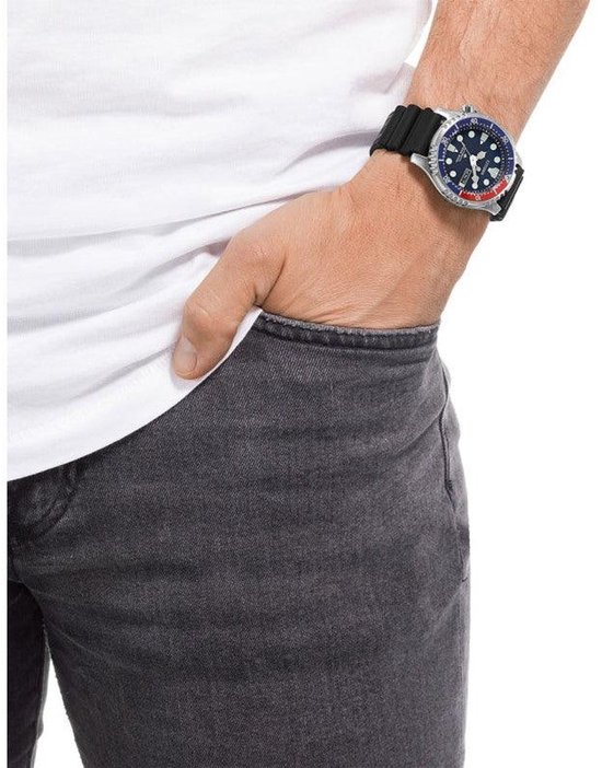 Man met een witte T-shirt en grijze jeans, draagt een Citizen Promaster duikhorloge.