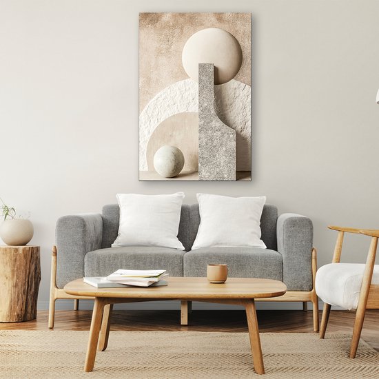 Œuvre d'art abstraite avec des formes beiges, blanches et grises, comme des cercles et des rectangles, au-dessus d'un canapé gris.