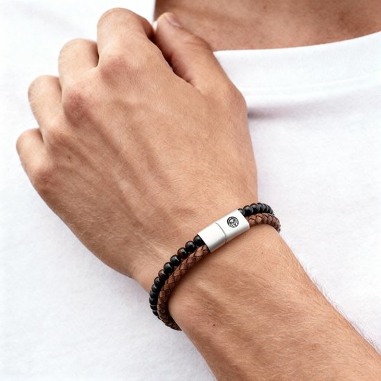 Close-up van een man die een armband met bruine en zwarte kralen en een metalen sluiting draagt.