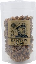 Een doorzichtige zak met bruine blokjes 'Kapitein Jacob Kabeljauw Vistrainers' en een etiket met een kapitein en hond.