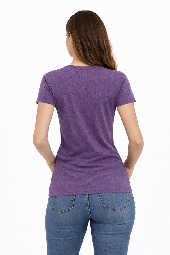 Vrouw met paars sportshirt met korte mouwen, jeans en handen in de zakken, van achteren gezien.