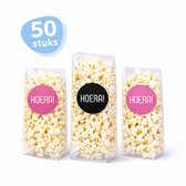 Drie doorzichtige zakjes gevuld met popcorn, met 'HOERA!' stickers in roze en zwart.