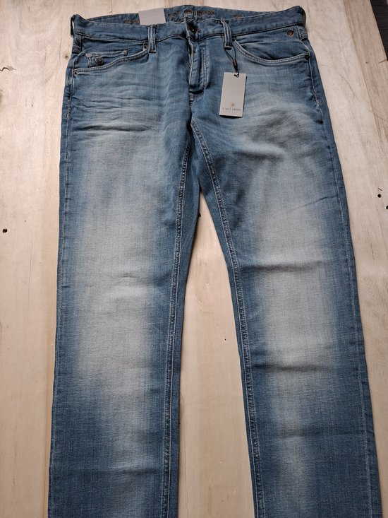 Lichtblauwe jeans met een lichte wassing en geleefde look. De broek ligt plat op een houten ondergrond.