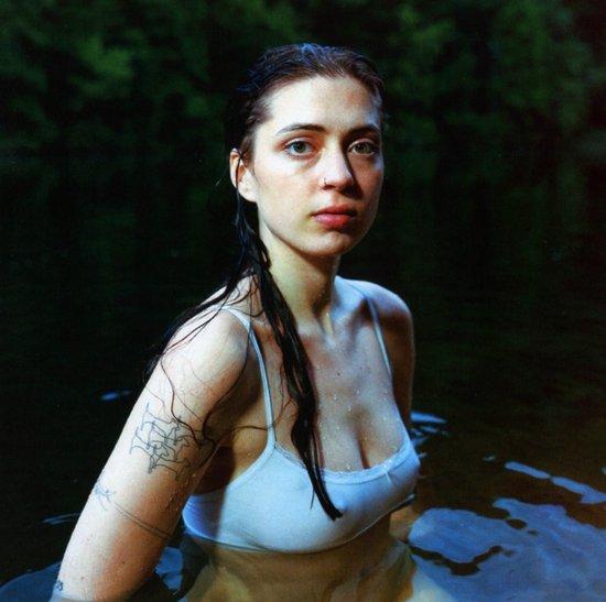 Een vrouw met lang, nat haar en een witte tanktop, omringd door donker water.