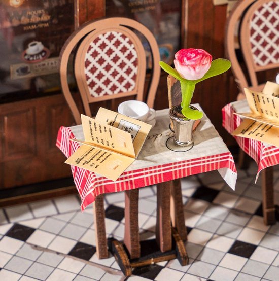 Een miniatuur cafétafel met rood-wit geblokt tafelkleed, menu's en een roze tulp in een zilveren houder.