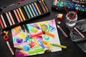 STABILO woody 3 in 1 ARTY potloden in een doos, naast een aquareltekening en losse potloden.