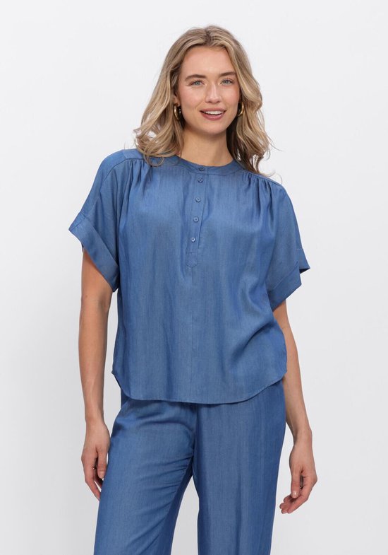 Blauwe blouse met ronde hals, knoopjes en korte, omgeslagen mouwen. Model draagt een bijpassende broek.