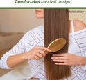 Vrouw met lang bruin haar kamt met een bamboe haarborstel.