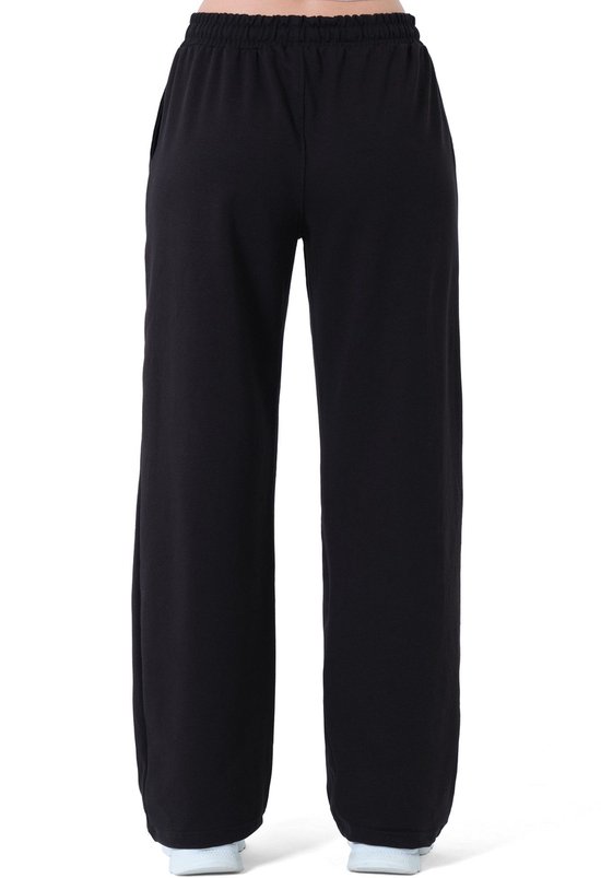Achterkant van een zwarte wijde joggingbroek gedragen door een model.
