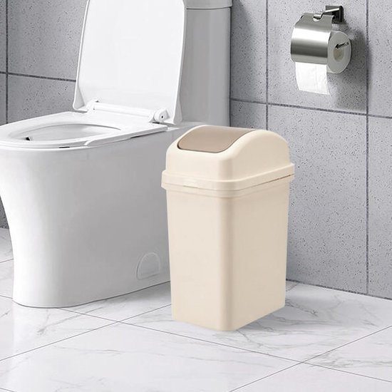 Beige afvalemmer met bruin kantel-deksel, naast een toilet in een betegelde badkamer.