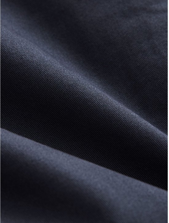 Detailopname van de textuur en stof van een marineblauwe chinobroek.