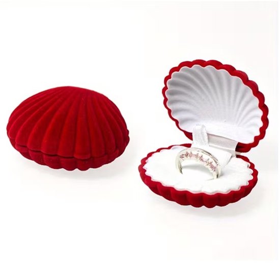 Rood fluwelen schelp sieradendoosje met een open klap en een zilveren ring met roze steentjes.