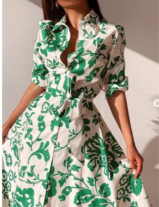 Close-up van een witte jurk met groene bloemenprint, lange jurk met ceintuur en lange mouwen.