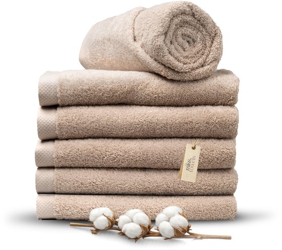 Stapel camelbruine handdoeken met opgerolde handdoek bovenop. Een kaartje met 'Miss Towels' en katoentakjes zijn zichtbaar.