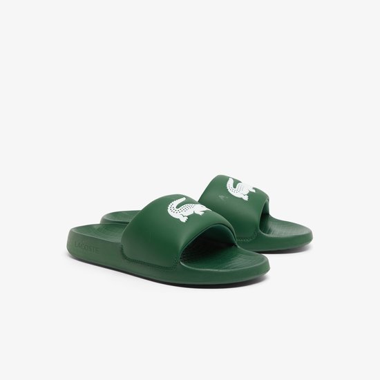 Donkergroene Lacoste slides met witte krokodillenlogo's. De zool is voorzien van een rasterpatroon.