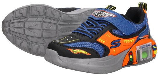 Blauwe sneaker met oranje accenten en een klittenbandsluiting. De schoen is naast een grijze zool geplaatst.