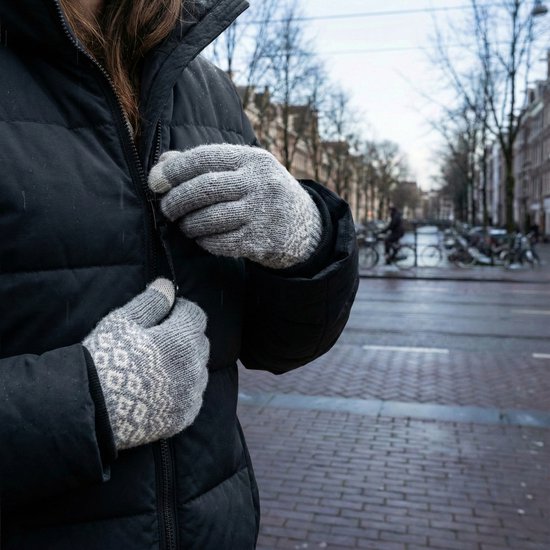 Grijze gebreide handschoenen met wit patroon, gedragen door een persoon met een zwarte jas.