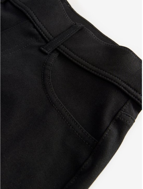 Detailopname van de zwarte jersey denim broek, met de tailleband, riemlussen en zak.