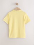 Achterkant van een effen lichtgeel poloshirt met korte mouwen, hangend aan een kledinghanger.