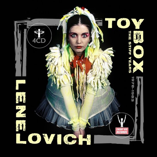 Lene Lovich in opvallende gele en witte outfit met franjes. Tekst: LENE LOVICH TOY BOX THE STIFF YEARS 1978-1983.