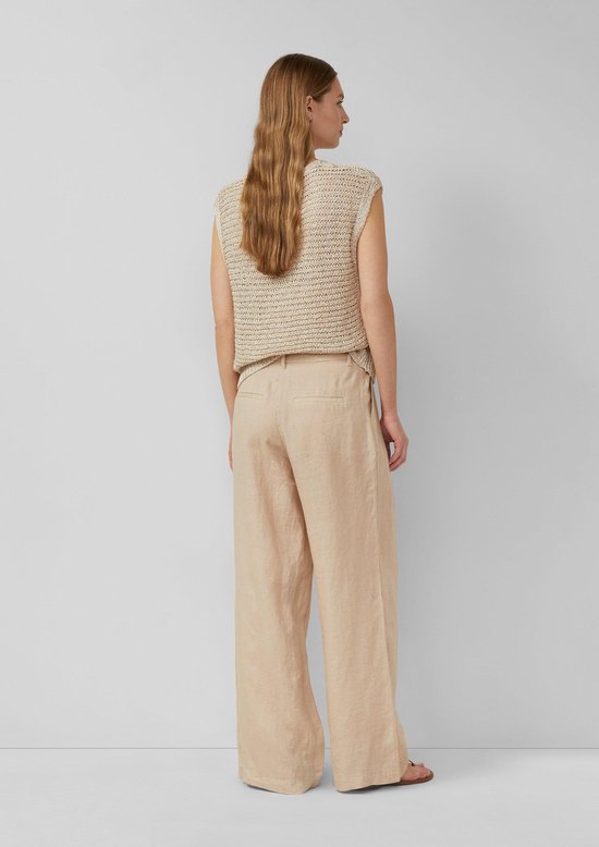 Zijaanzicht van een model in een beige gebreide top en een wijde beige linnen broek.