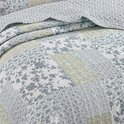 Quilt met patchwork van bloemenprints en ruitpatronen in blauw, groen en wit.