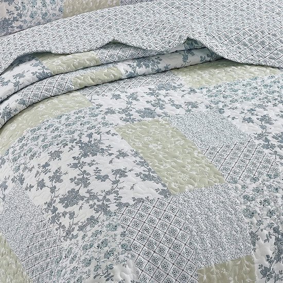 Quilt met patchwork van bloemenprints en ruitpatronen in blauw, groen en wit.