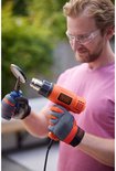 Man met veiligheidsbril en oranje werkhandschoenen gebruikt een oranje Black+Decker verfbrander op een rond object.