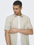 Man met een beige linnen mix overhemd met korte mouwen en een witte t-shirt.