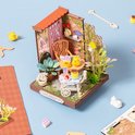 Miniatuur 'Fancy Tea Yard' model met geel theeservies, gebak en een witte kat.
