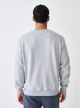 Achteraanzicht van een man in een grijze sweater met ronde hals en donkerblauwe joggingbroek.