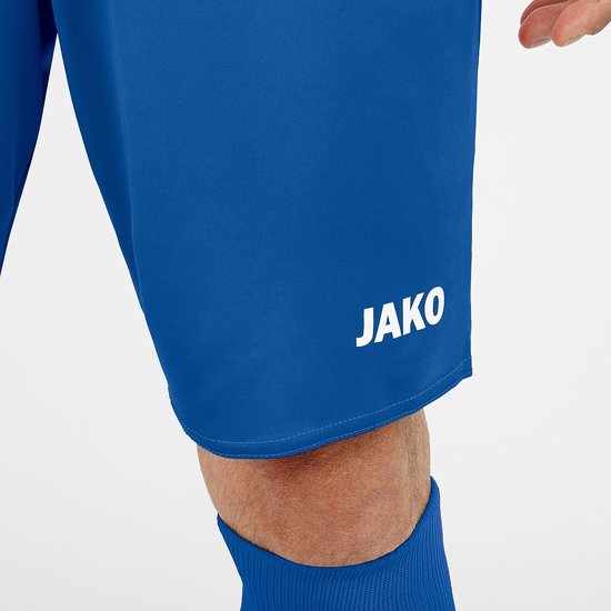 Gros plan sur la cuisse droite d'un short de sport bleu avec un logo Jako.