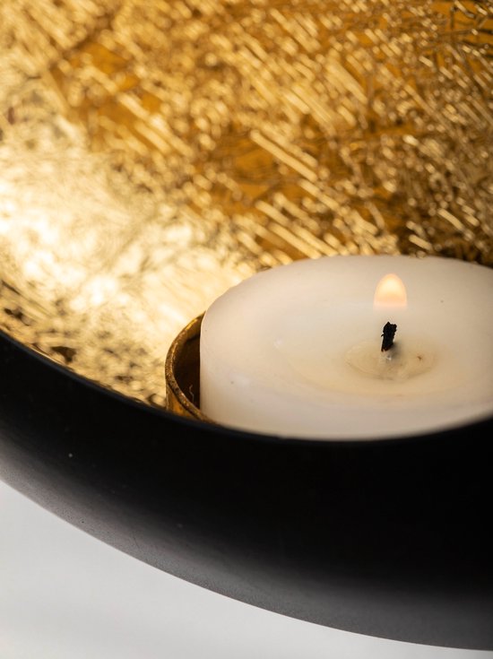 Bougie blanche dans un bougeoir doré et noir.