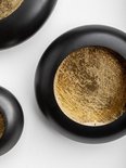 Trois bougeoirs muraux ronds noirs avec intérieur doré.