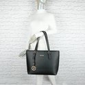 Un mannequin porte le sac cabas noir Gallantry avec logo G doré.