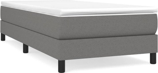 Grijs gestoffeerd bed met witte topper en zwarte pootjes.