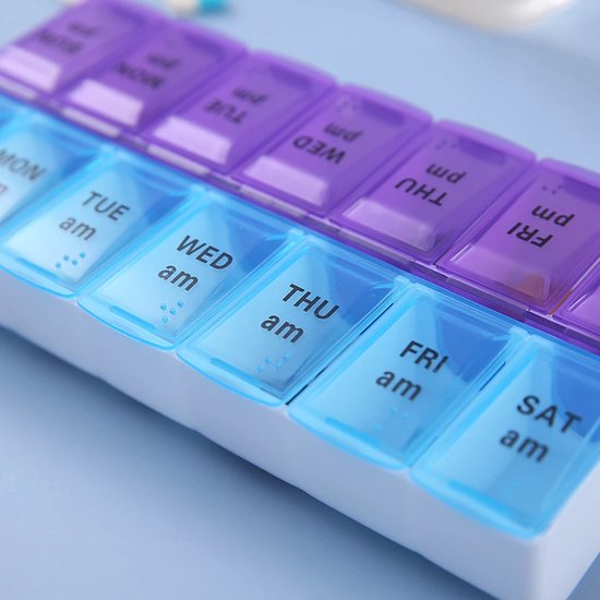 Medicijndoos met 14 vakjes, met 'MON am' tot 'FRI am'. Blauwe en paarse deksels.