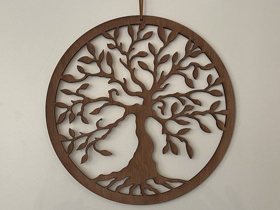 Décoration murale ronde en bois marron avec un motif d'arbre de vie, sur un mur blanc.