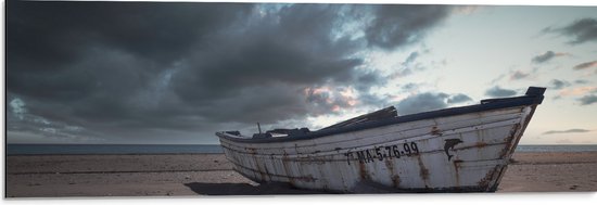WallClassics - Dibond - Witte Boot op het Strand onder Donkere Wolken - 90x30 cm Foto op Aluminium (Wanddecoratie van metaal)