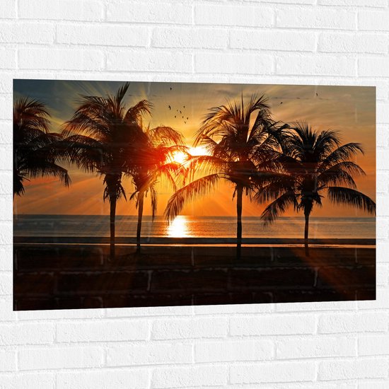 WallClassics - Muursticker - Palmbomen op het Strand bij Zonsondergang - 105x70 cm Foto op Muursticker