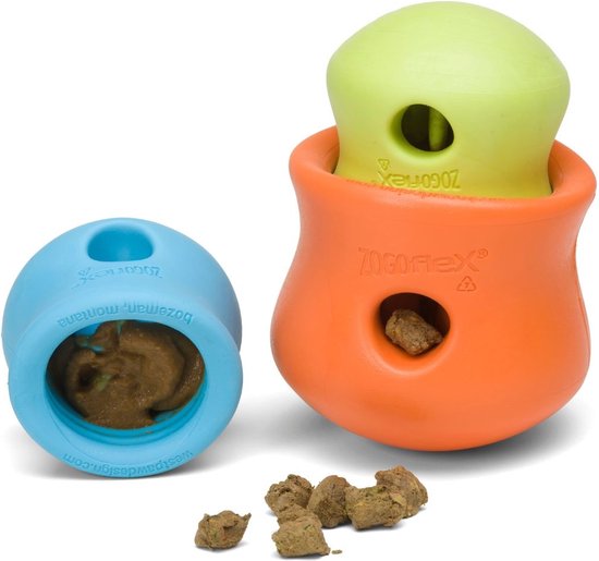 Blauw Zogoflex speeltje gevuld met voer, naast een oranje en groen speeltje. Rondom liggen brokken voer.