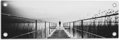 WallClassics - Tuinposter – Persoon op Brug bij het Water in het zwart-wit - 60x20 cm Foto op Tuinposter  (wanddecoratie voor buiten en binnen)
