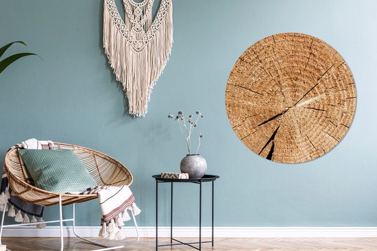 Décoration murale ronde en bois avec cernes annuels à côté d'une chaise en rotin.