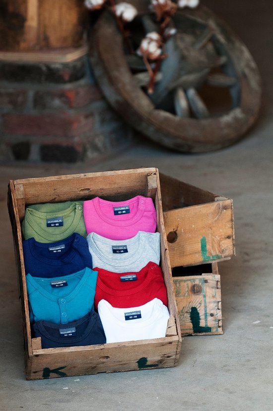Een houten kist met daarin acht babyrompers in verschillende kleuren: groen, roze, donkerblauw, grijs, turquoise, rood, zwart en wit.